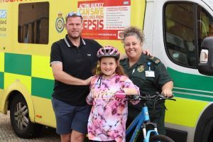 grace standing in front of an ambulance with her bicycle