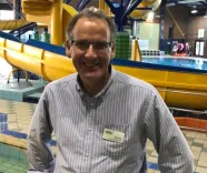  A man wearing glasses standing in front of a water slide