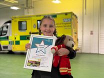 Bunny-Mae Dale, 7, stands proudly in front of an ambulance with a bravery certificate and a teddy bear, presented to her by Suffolk Accident Rescue Service