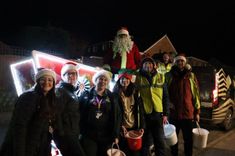 A group of six people with fundraising buckets in front of sleigh with a man dressed as Santa Clausa