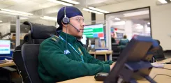 EEAST staff sat at a desk, wearing a headset, working on his computer