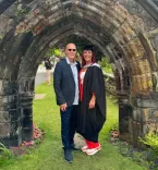 Two people standing in front of a stone arch