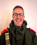 A head and shoulders picture of Liam Sagi in ambulance uniform with red epaulettes visible indicating his advanced practitioner roles