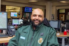 Male call handler in headset smiling at the camera, sitting in the control room