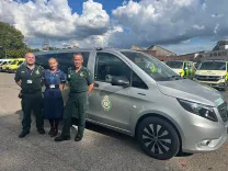 Three clinicians stand in front of the new electric mental health response vehicle