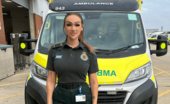 Paramedic Phoebe Grace, in uniform, standing in front of an ambulance at Southend Ambulance Station