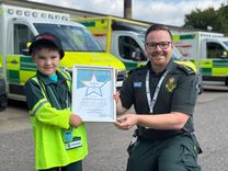 A four-year-old boy is presented with a certificate of recognition by a paramedic