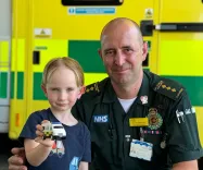 Photo of a paramedic and a young boy holding a toy ambulance