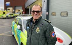 Community First Responder Stuart Little in green ambulance uniform standing in front of a response car at Chelmsford Ambulance Station