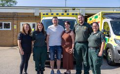 Tony Pearce stands with his wife, Claire, and four East of England Ambulance Service staff members in front of an ambulance following a reunion with the team who responded to his road traffic collision in March 2024.