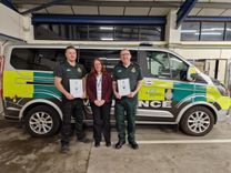 Two emergency care assistants and a leader development manager stood in front of an EEAST vehicle