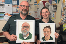 Photo of two paramedics receiving their painted portraits